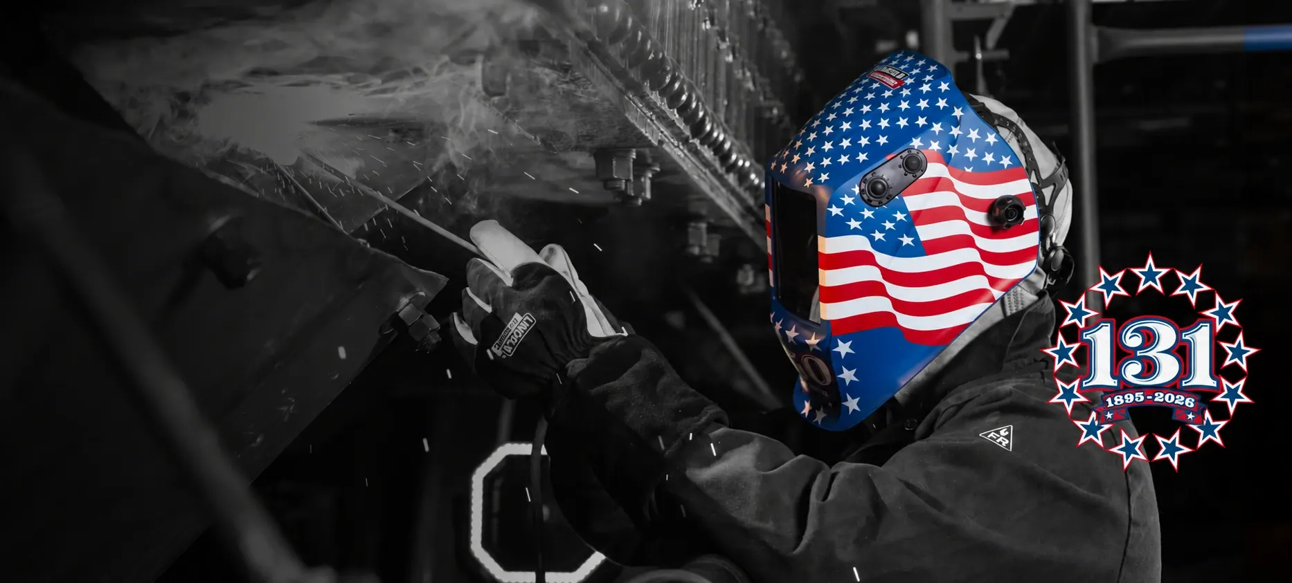 Welder wearing an American flag welding helmet beside a 131 anniversary emblem dated 1895–2026